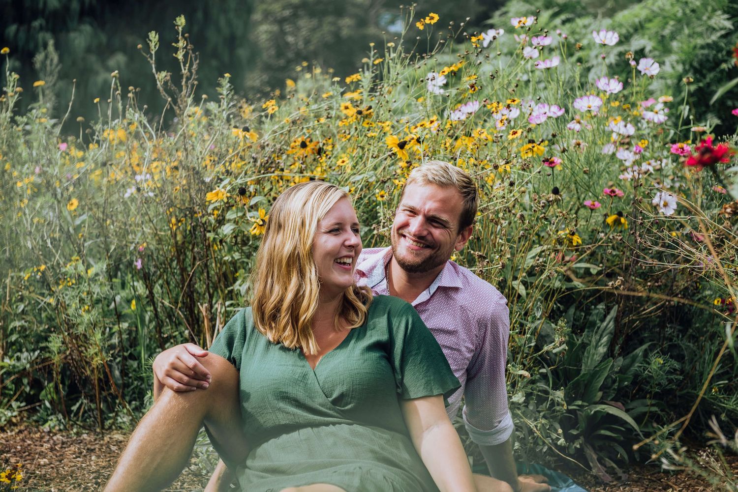 Couple laughing while sitting surrounded by wildflowers in Botanical Gardens - Zara King Photography, Sydney Australia