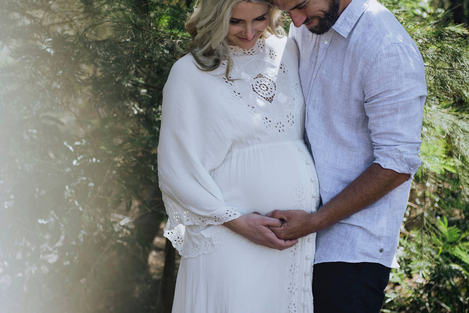 Pregnant woman and husband holding her belly during at-home session - Zara King Photography, Sydney Australia