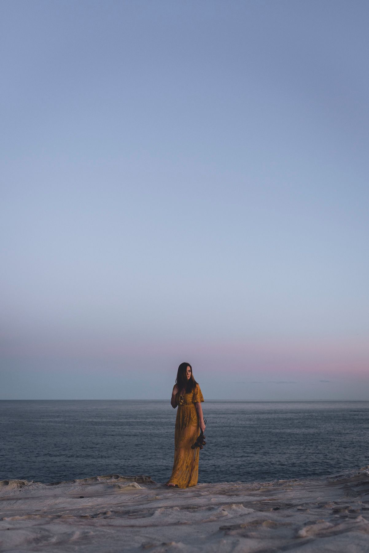 Zara King holding dried flowers walking along a cliff at sunset - Zara King Photography, Sydney Australia