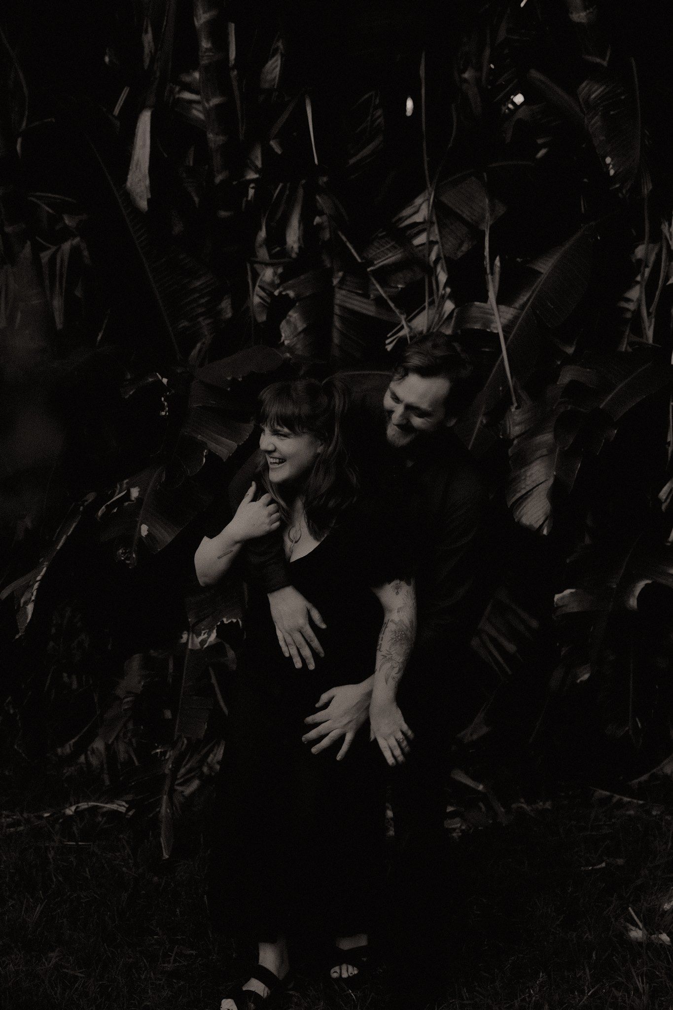 Zara King and fiancé giggling in front of banana trees