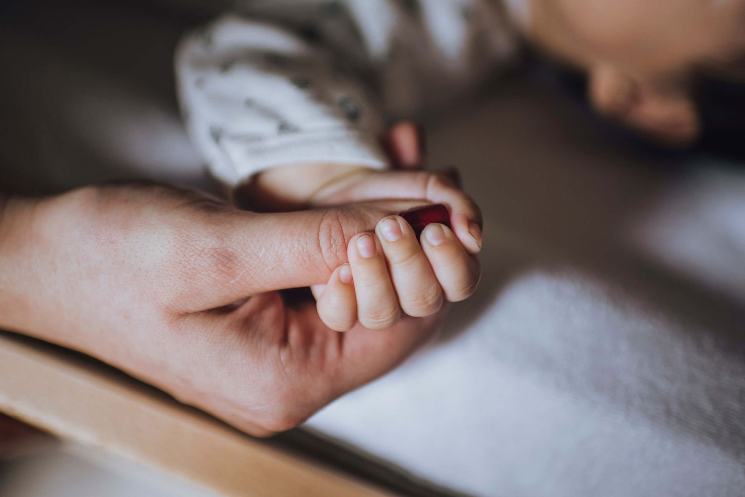 Dad holding newborn baby's hand during in-home session - Zara King Photography, Sydney Australia