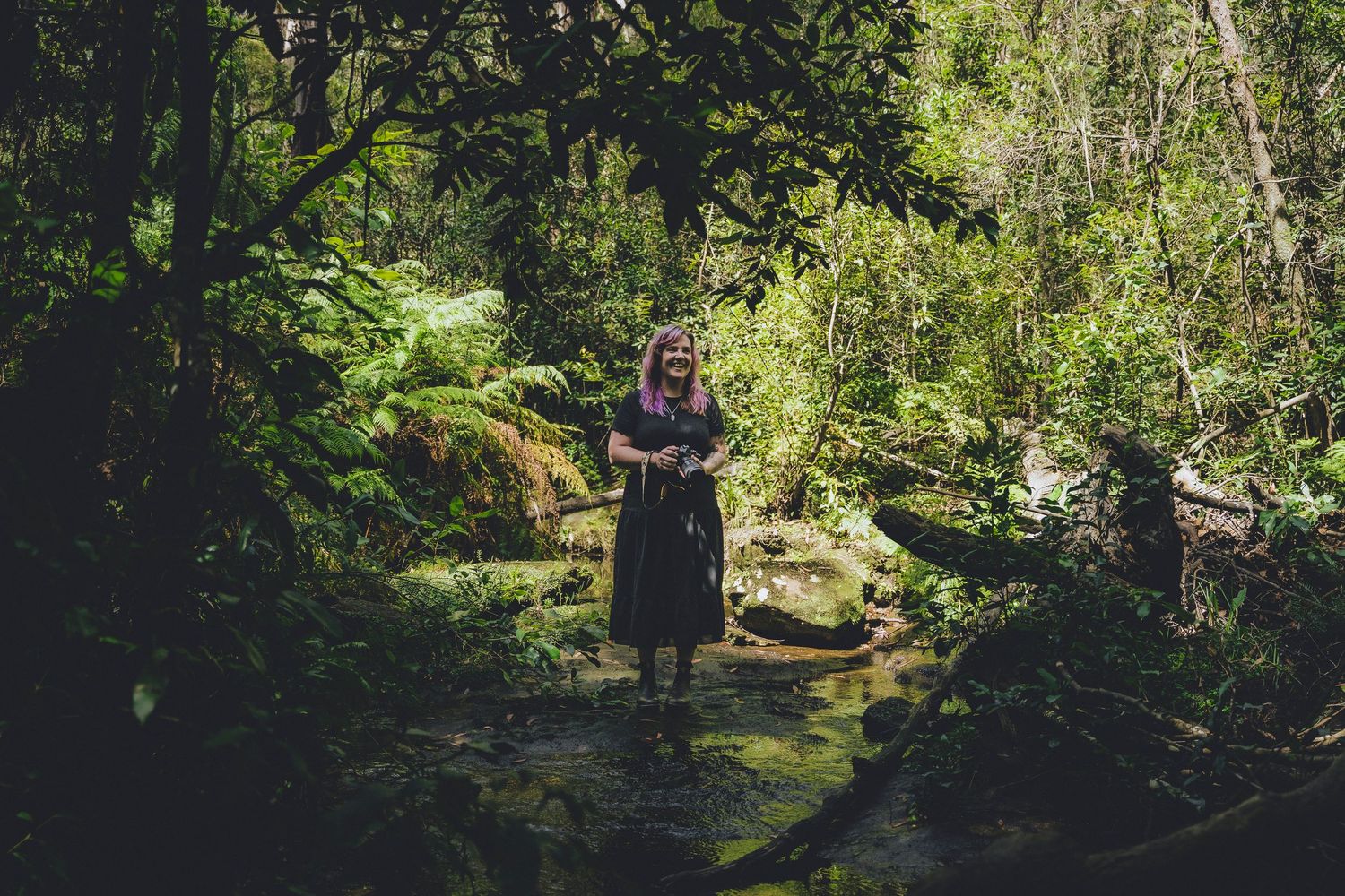 Portrait of Zara King laughing and holding her camera amongst nature - Zara King Photography, Sydney Australia