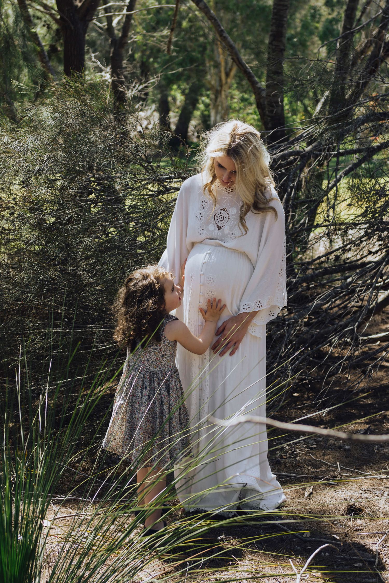 Pregnant woman and toddler daughter touching her belly during at-home session - Zara King Photography, Sydney Australia