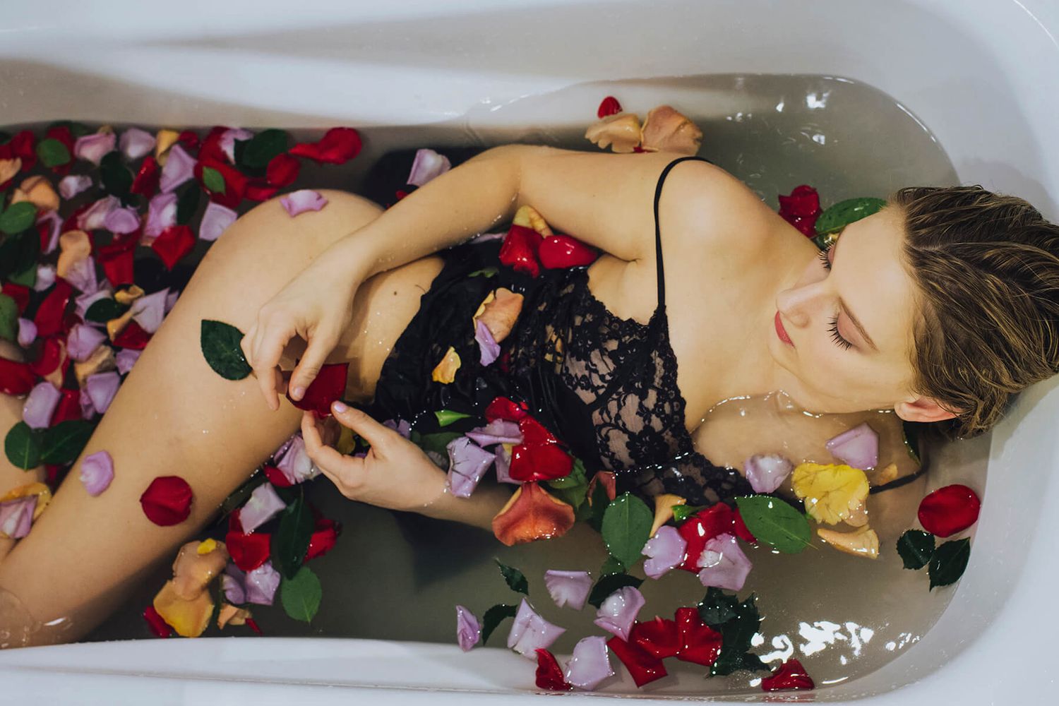 Girl wearing black silky dress in bathtub surrounded by rose petals during modelling photo shoot - Zara King Photography, Sydney Australia