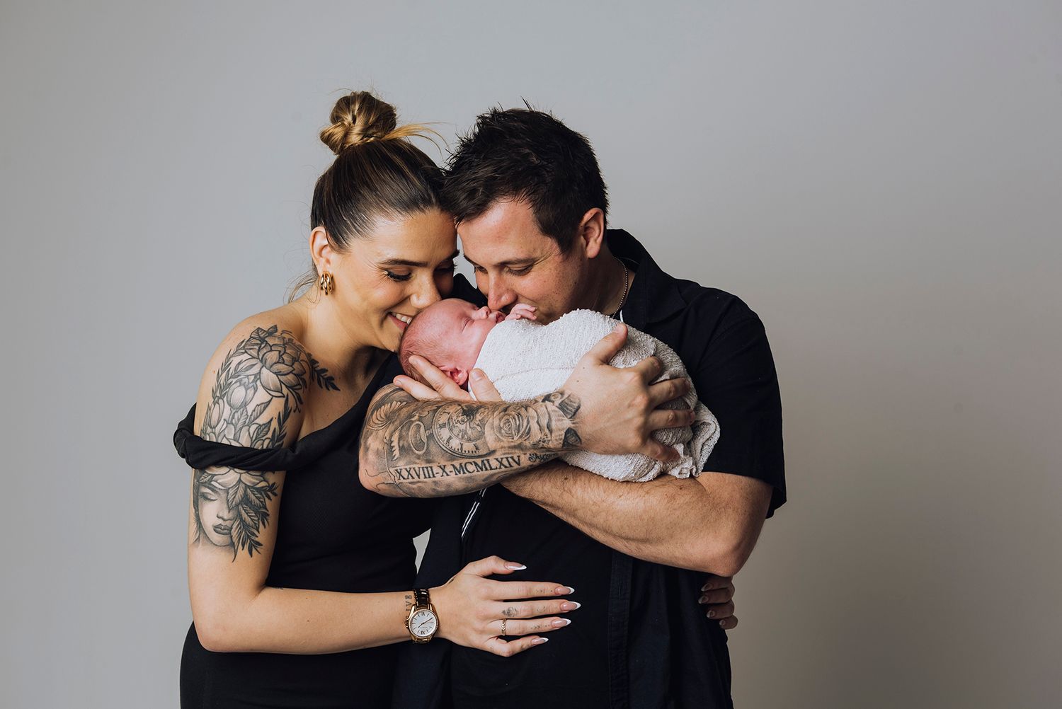Mum and dad giggling while kissing their newborn baby - Zara King Photography, Sydney Australia
