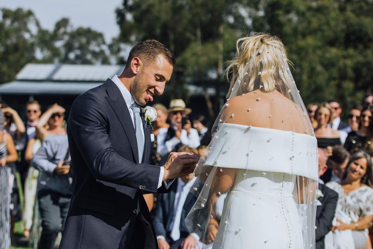 Groom sticks tongue out while putting ring on bride's finger during their ceremony in Kangaroo Valley - Zara King Photography, Sydney