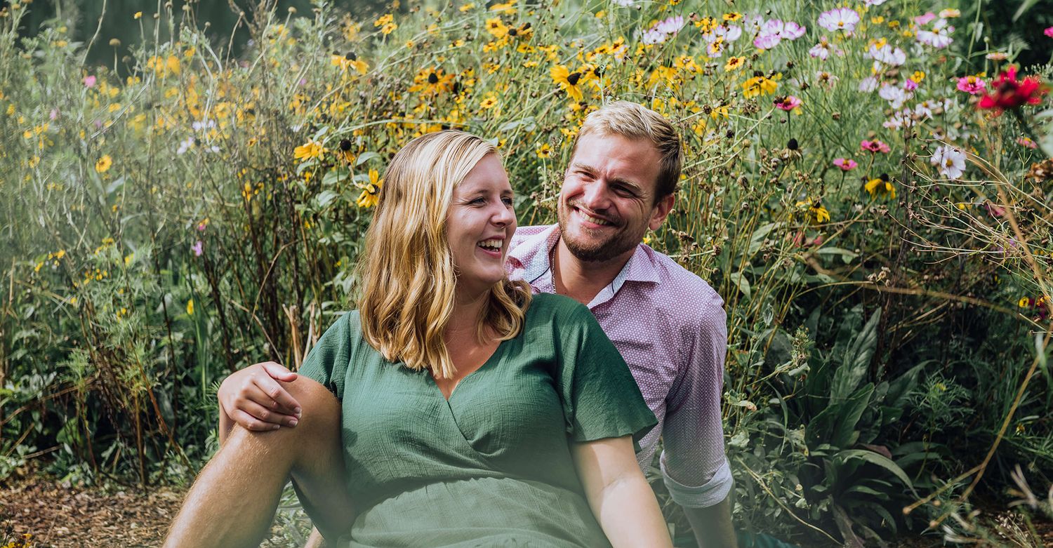 Couple laughing while sitting surrounded by wildflowers in Botanical Gardens - Zara King Photography, Sydney Australia