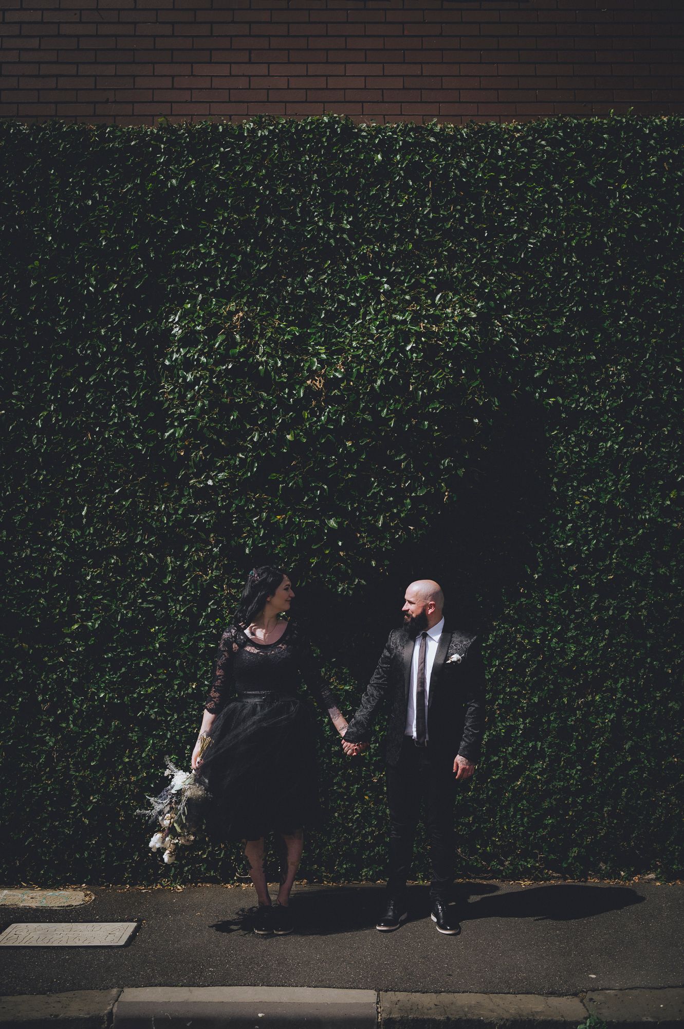 Alternative newlywed couple both in black holding hands - Zara King Photography, Melbourne Australia