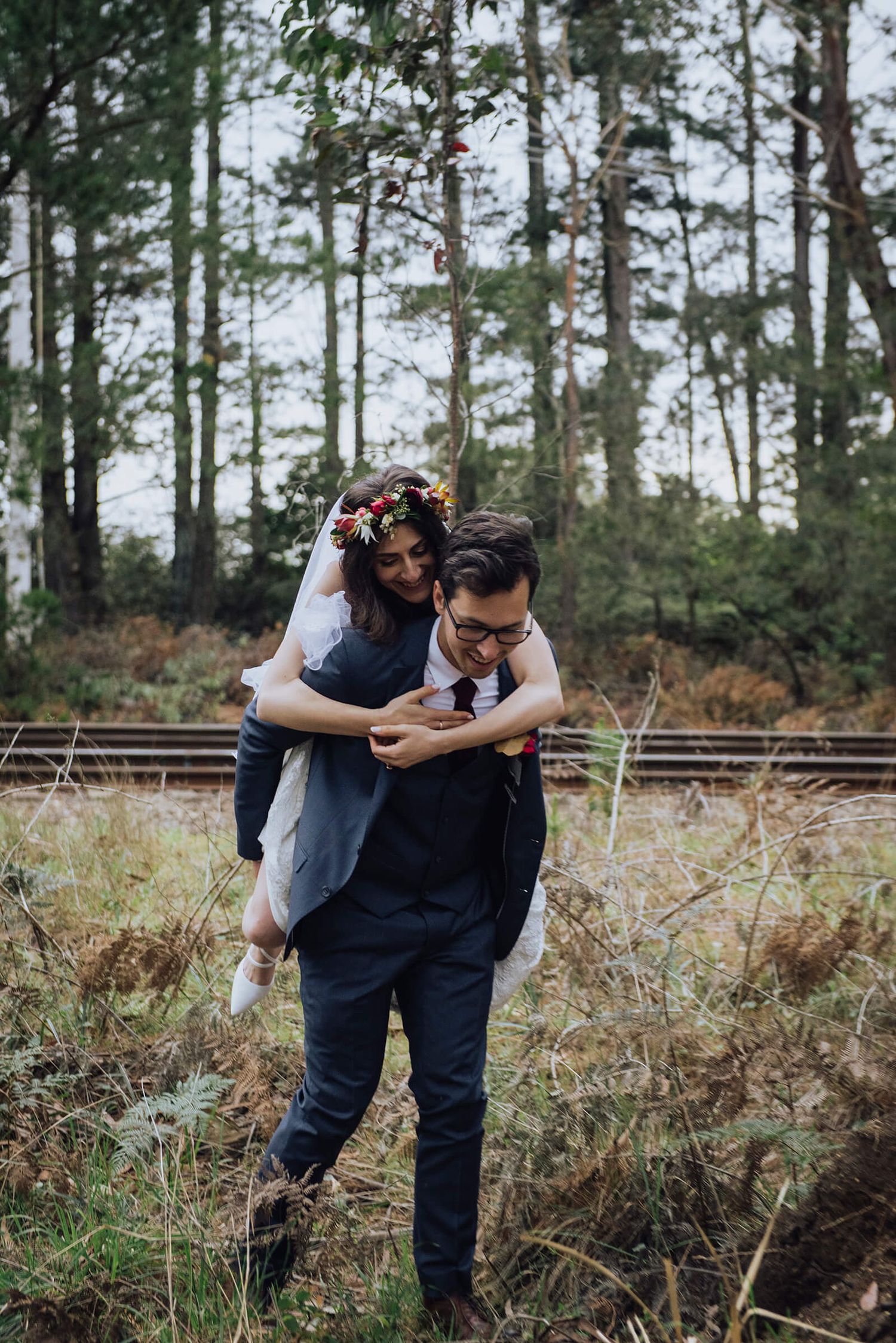 Groom carries bride on his back during bridal party photos in Southern Highlands - Zara King Photography, Sydney Australia