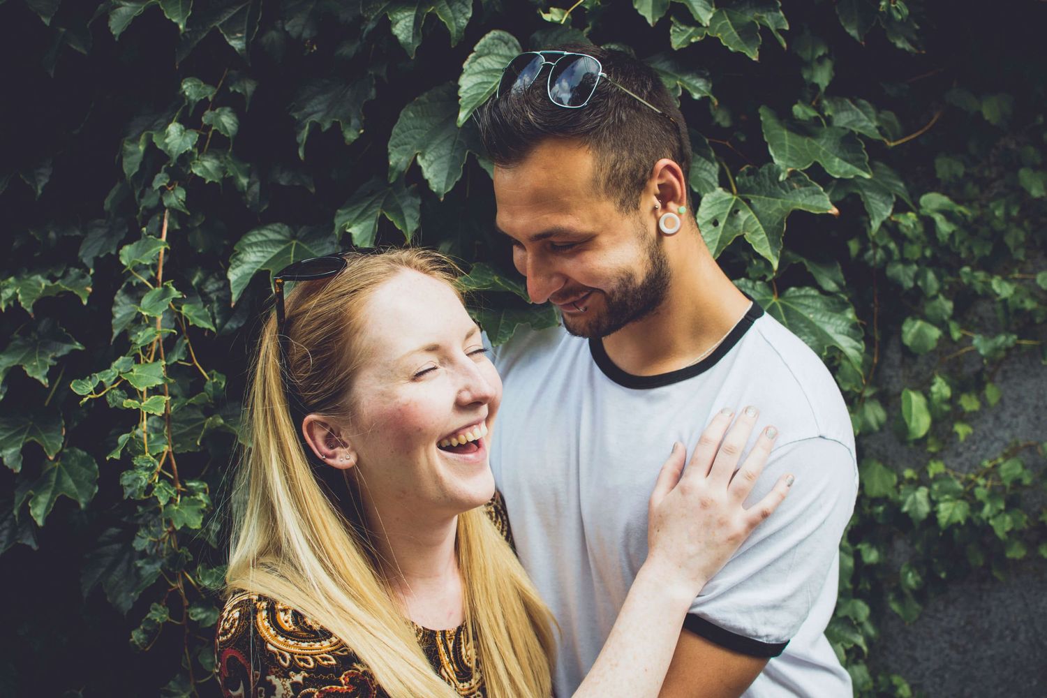 Couple cuddling and laughing in front of ivy in Newtown - Zara King Photography, Sydney Australia