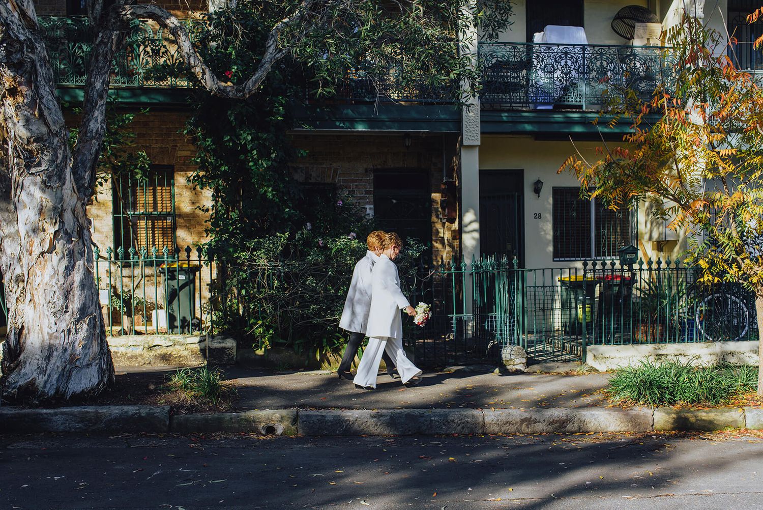 Two brides walking down the street holding hands in Newtown - Zara King Photography, Sydney Australia