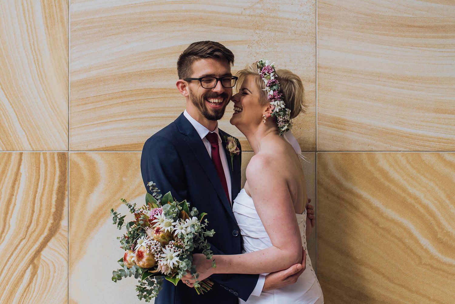 Bride and groom giggling in front of sandstone wall - Zara King Photography, Sydney Australia