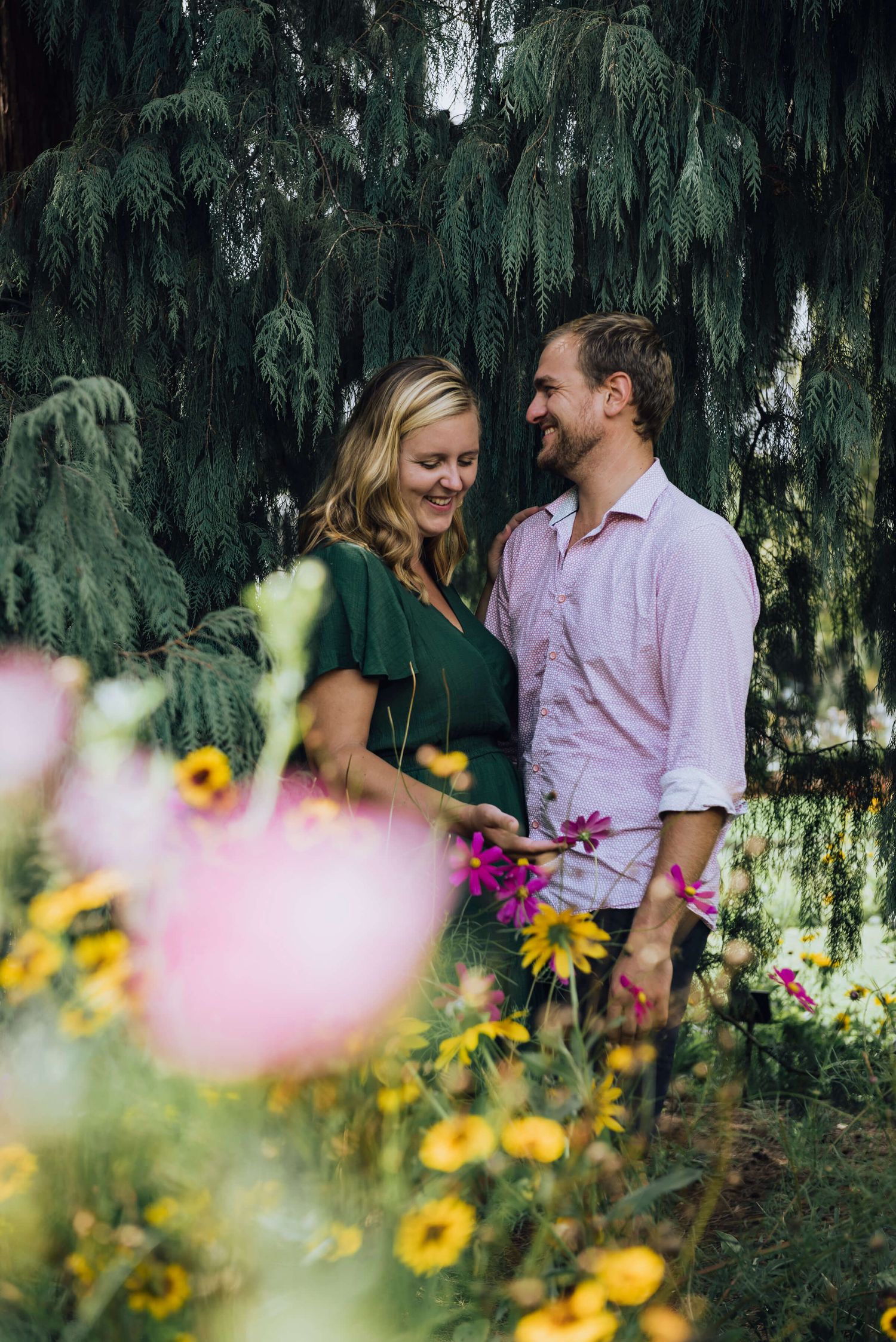 Couple cuddling and laughing surrounded by wildflowers in Botanical Gardens - Zara King Photography, Sydney Australia