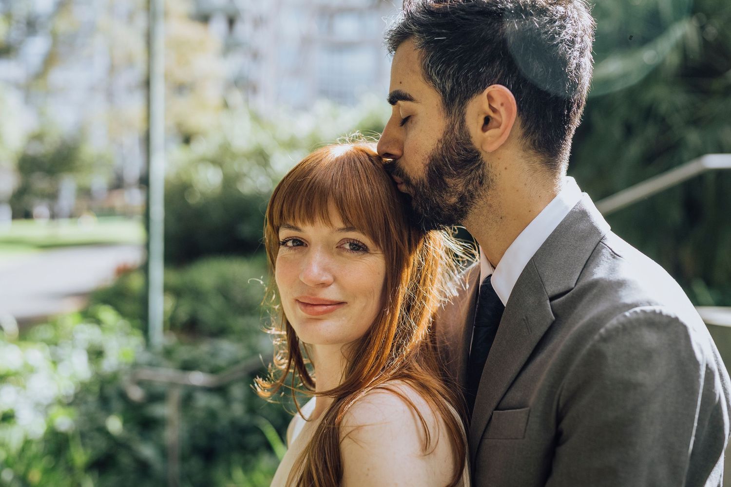 Groom kissing bride's head while bride looks into camera - Zara King Photography, Melbourne Australia