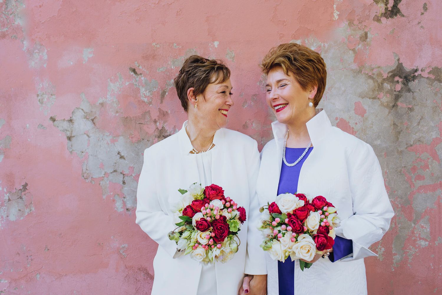 Two brides laughing in front of pink wall in Newtown - Zara King Photography, Sydney Australia