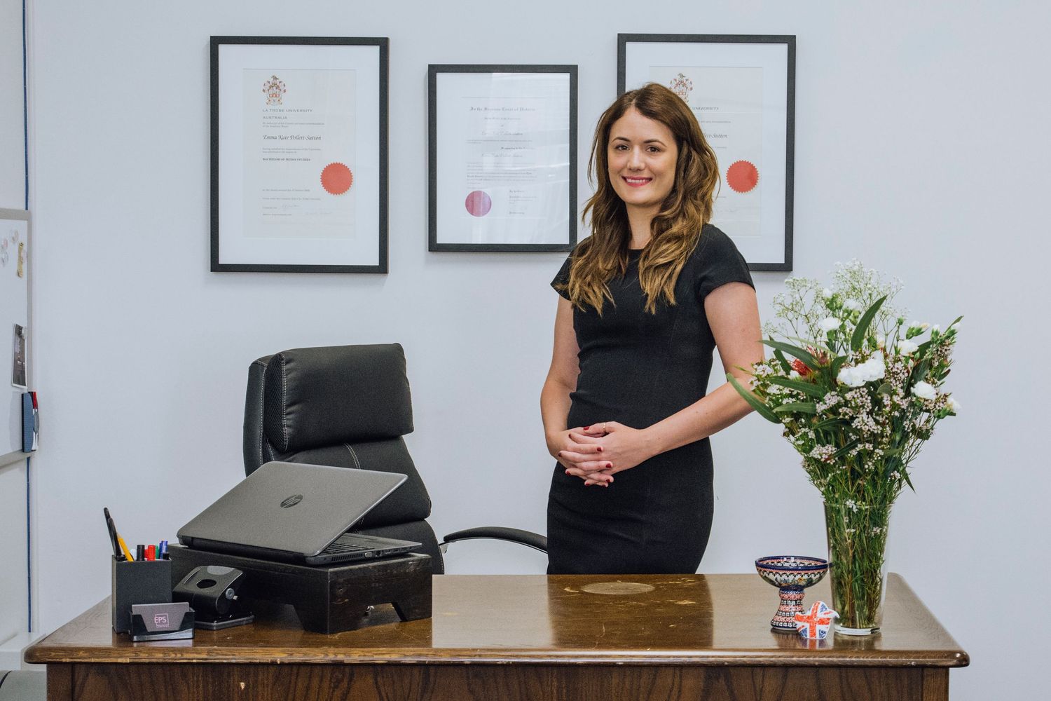 Lawyer standing behind her desk with her awards on the wall during in-house creative headshot session in Gosford- Zara King Photography