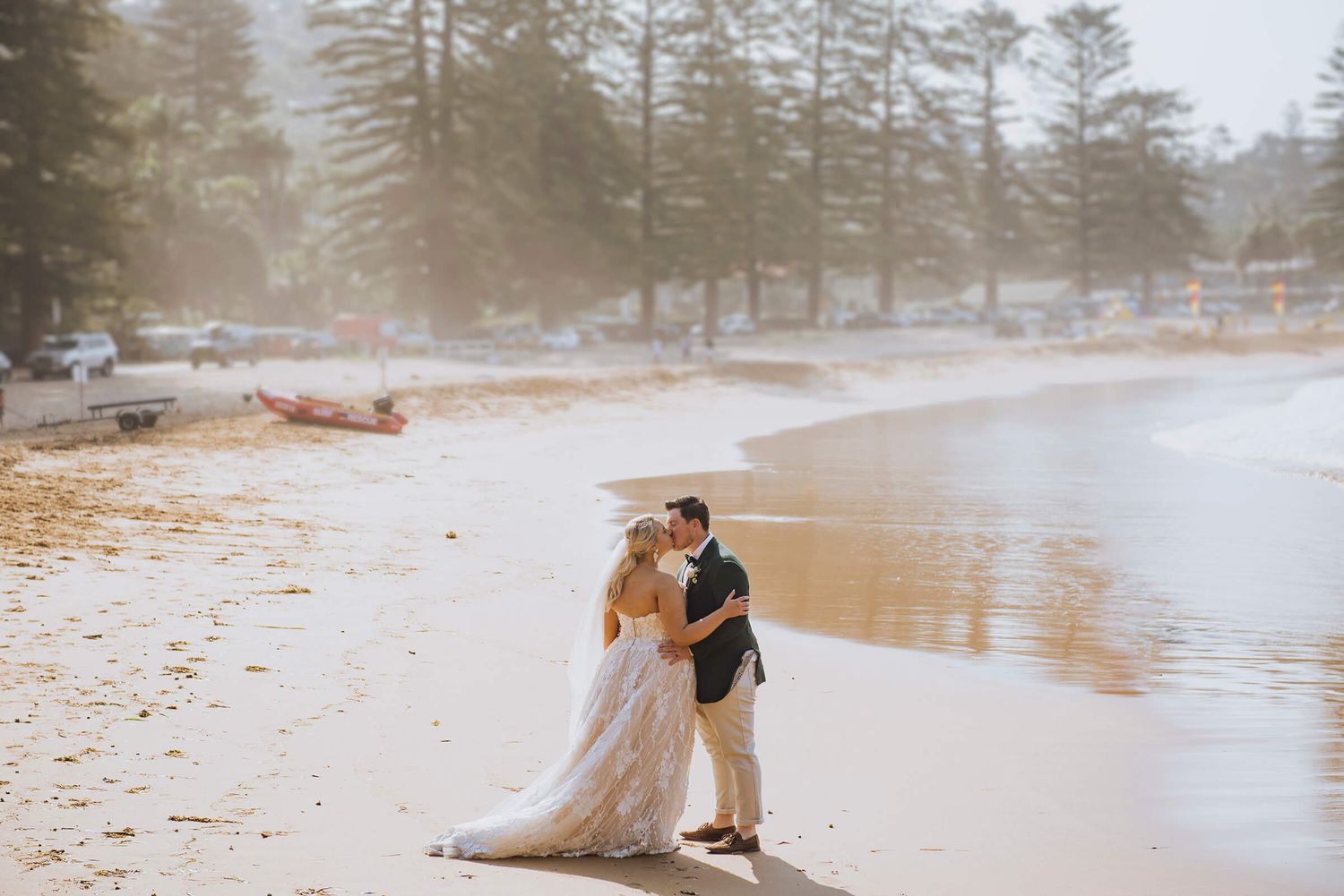 Bride and groom kissing on the beach surrounded by salt spray in Palm Beach - Zara King Photography, Sydney Australia