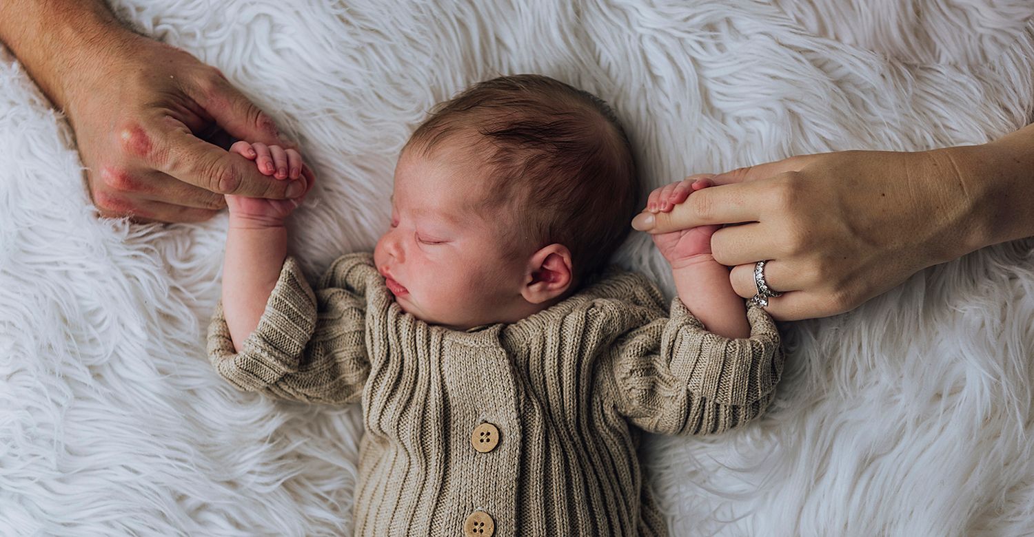 Newborn baby asleep on her back while she's holding both of her parents index fingers - Zara King Photography, Sydney Australia