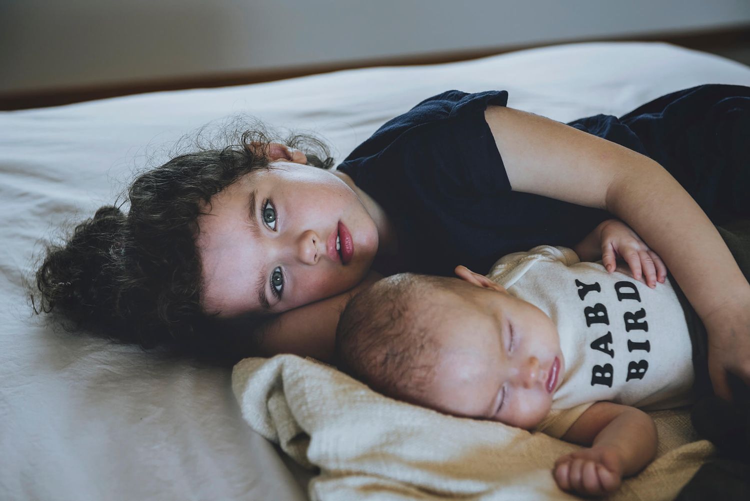 Toddler older sister cuddles newborn brother during in-home session - Zara King Photography, Sydney Australia