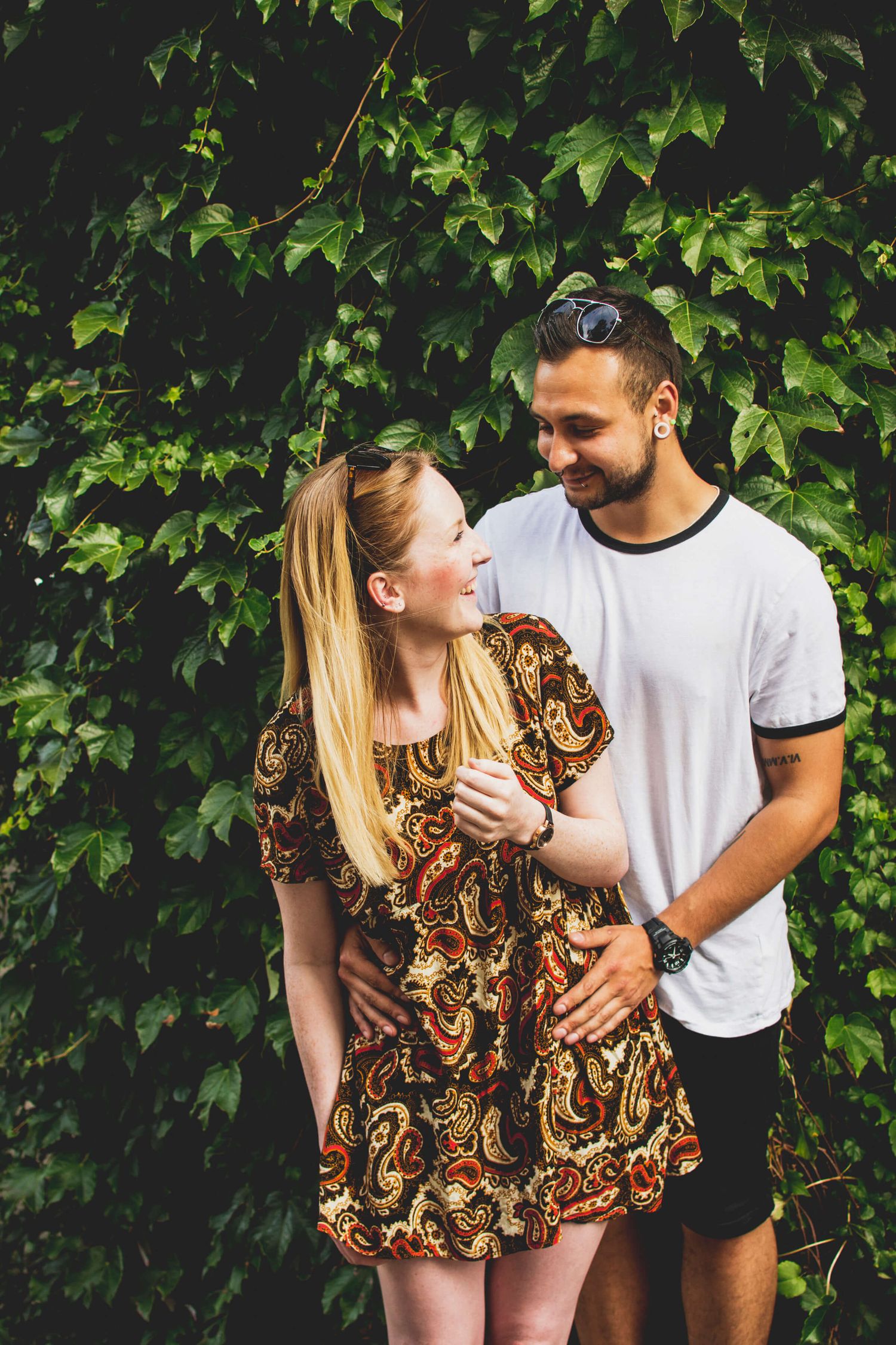 Couple cuddling and looking at each other in front of ivy in Newtown - Zara King Photography, Sydney Australia