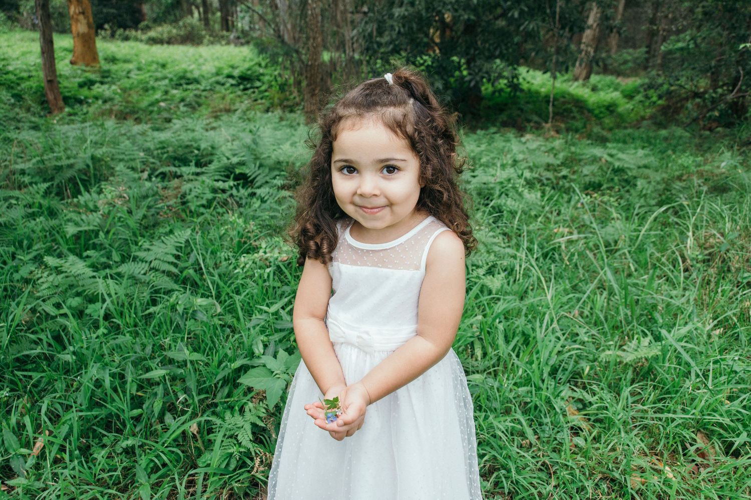 Toddler girl holding flowers she picked during outdoor family session - Zara King Photography, Sydney Australia