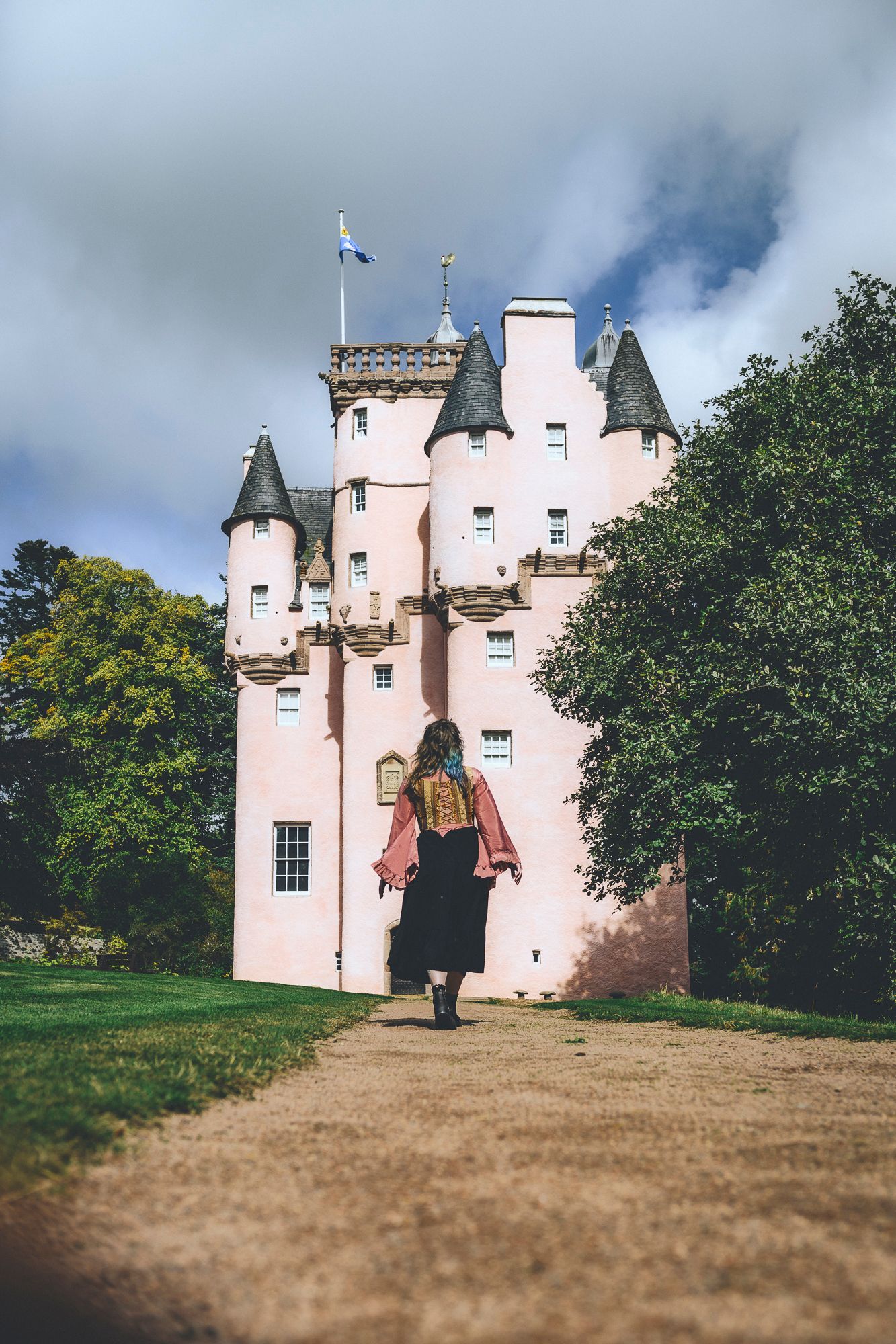Zara King walking towards a pink castle in Scotland - Zara King Photography