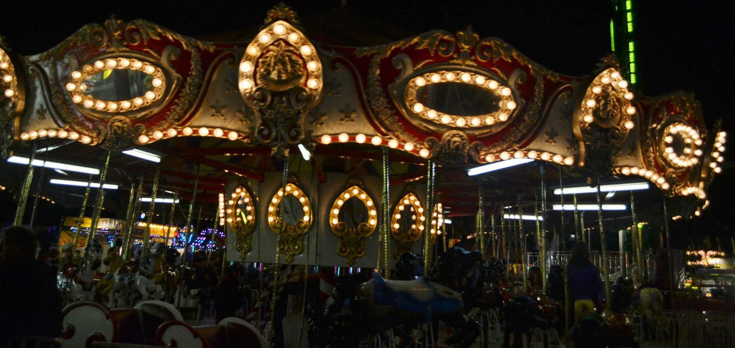 Brightly lit carousel with ornate golden decorations glowing at night at the Iowa State Fair.