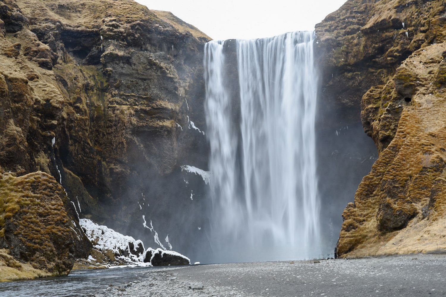 Majestic Skogafoss waterfall plunges between towering rocky cliffs in Iceland.