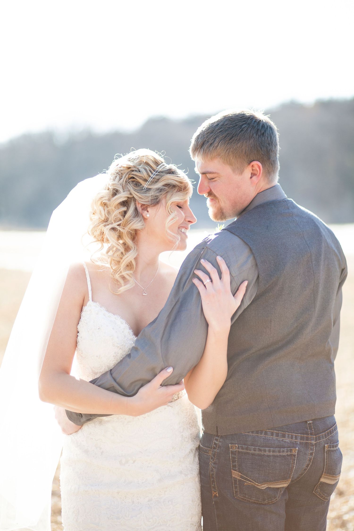 A bride and groom share an intimate moment on a sunny beach during their wedding photoshoot.