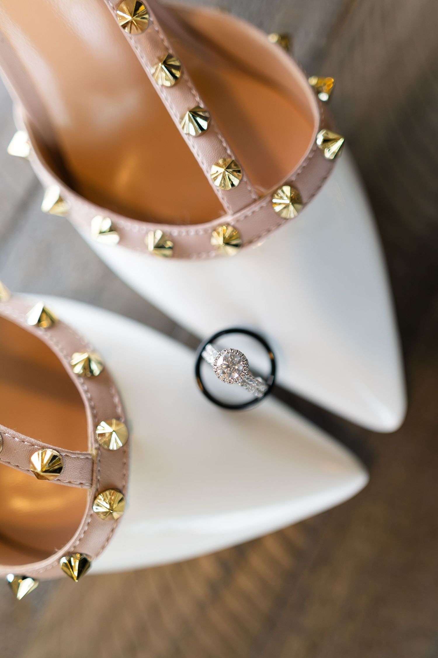White studded wedding shoe with engagement ring captured through magnifying glass.