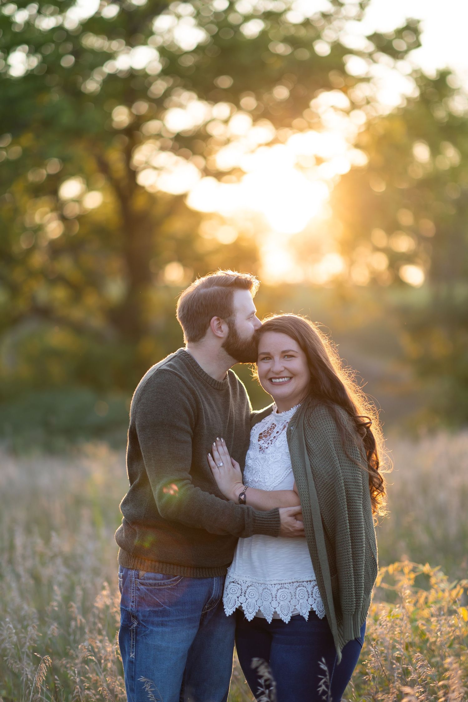 A couple sharing a tender moment in a sunlit field during golden hour.