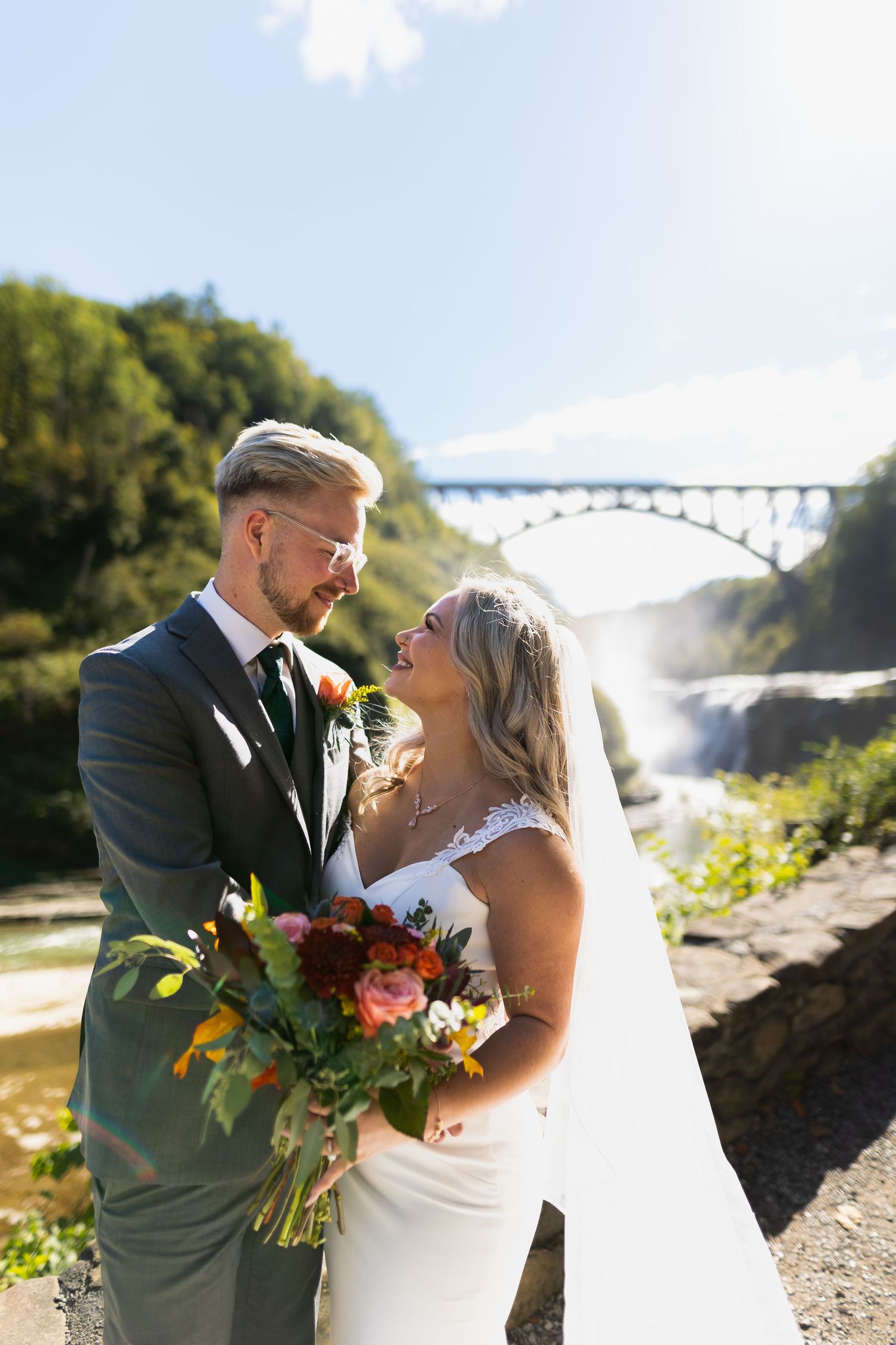 A romantic wedding portrait taken near Letchworth State Park bridge with fall foliage in the background.