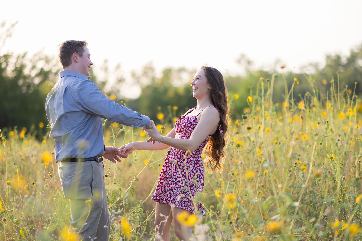 Couple dancing together in a sunlit meadow filled with yellow wildflowers.