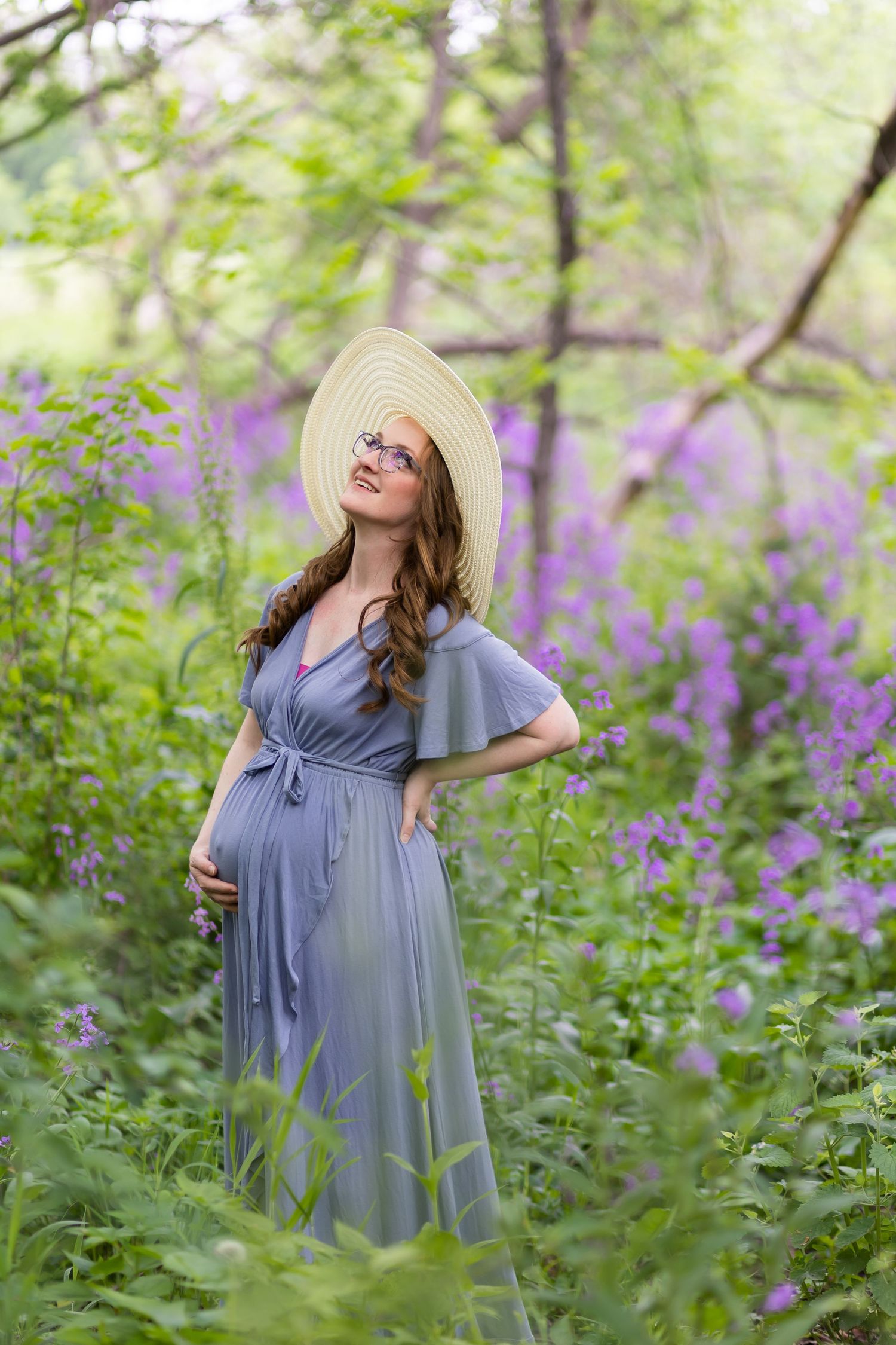 A maternity portrait in a lavender field with woman wearing blue dress and sun hat.