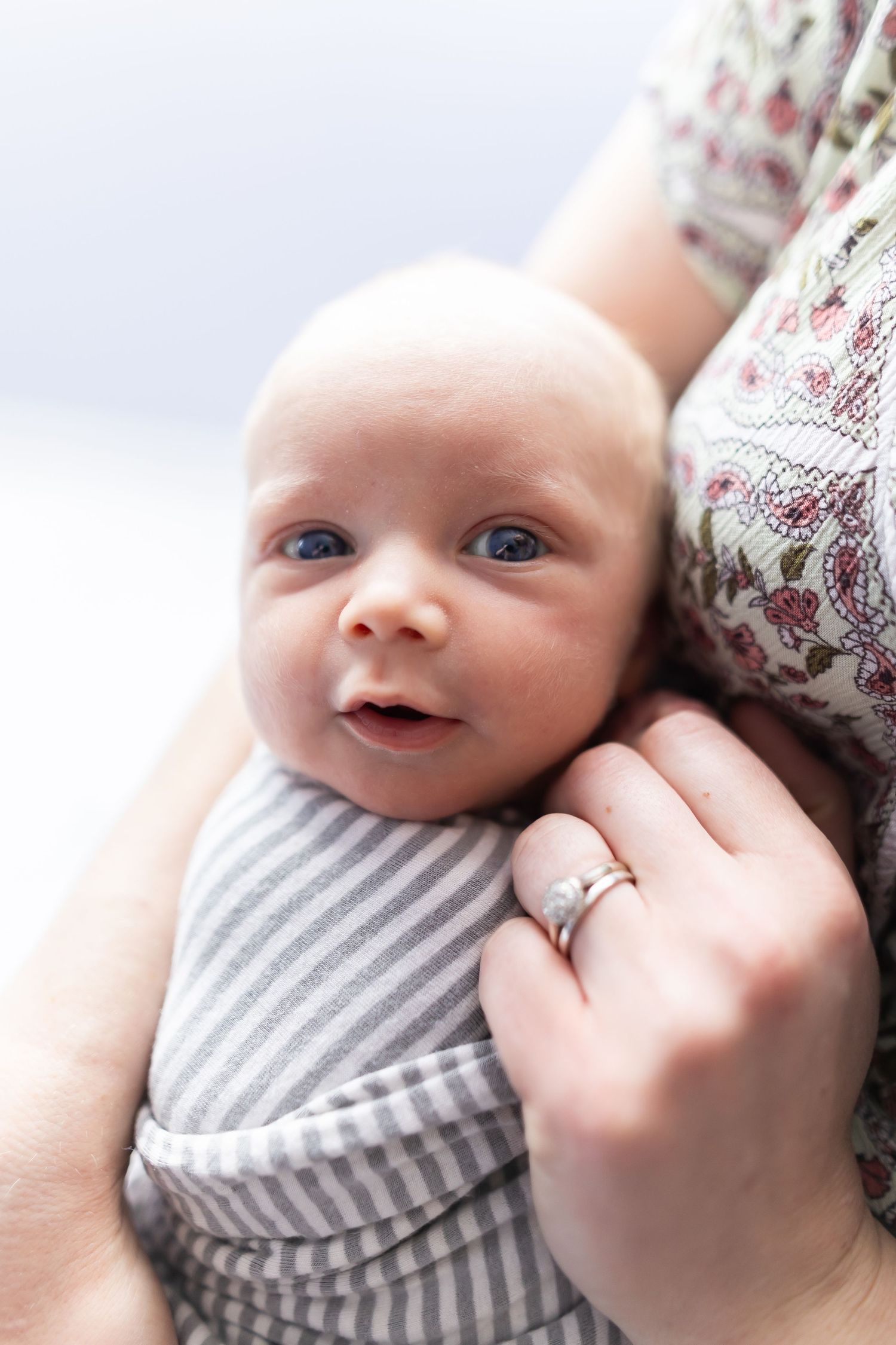 Close-up portrait of an infant in striped clothing being held.