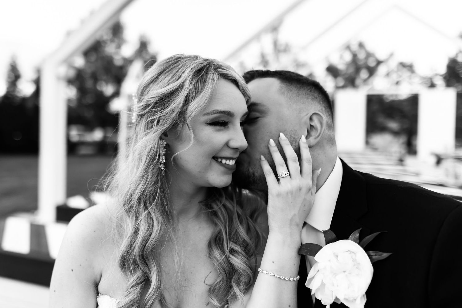 A romantic black and white portrait of a happy newlywed couple sharing an intimate moment in their wedding attire.