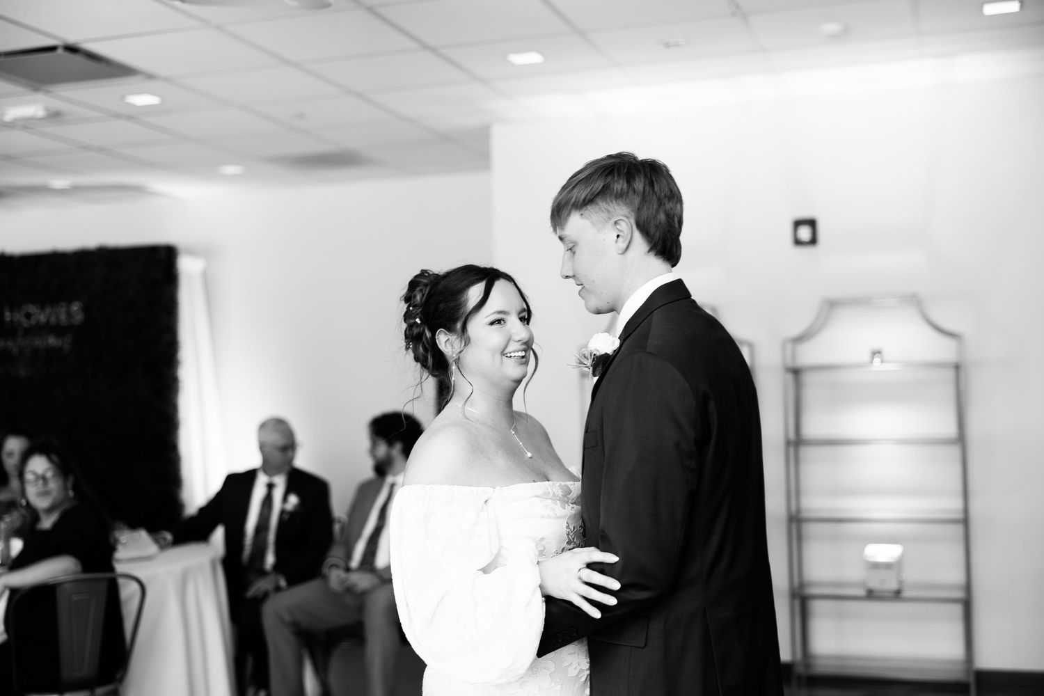 Black and white photo of a bride and groom sharing their first dance at an elegant wedding reception.
