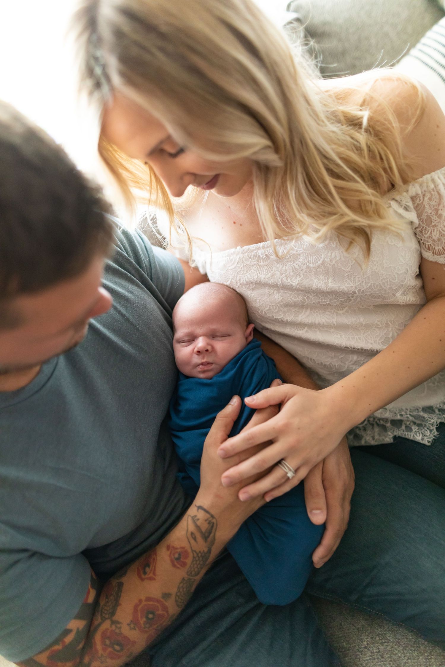 An intimate family moment with a sleeping newborn between parents in soft lighting.
