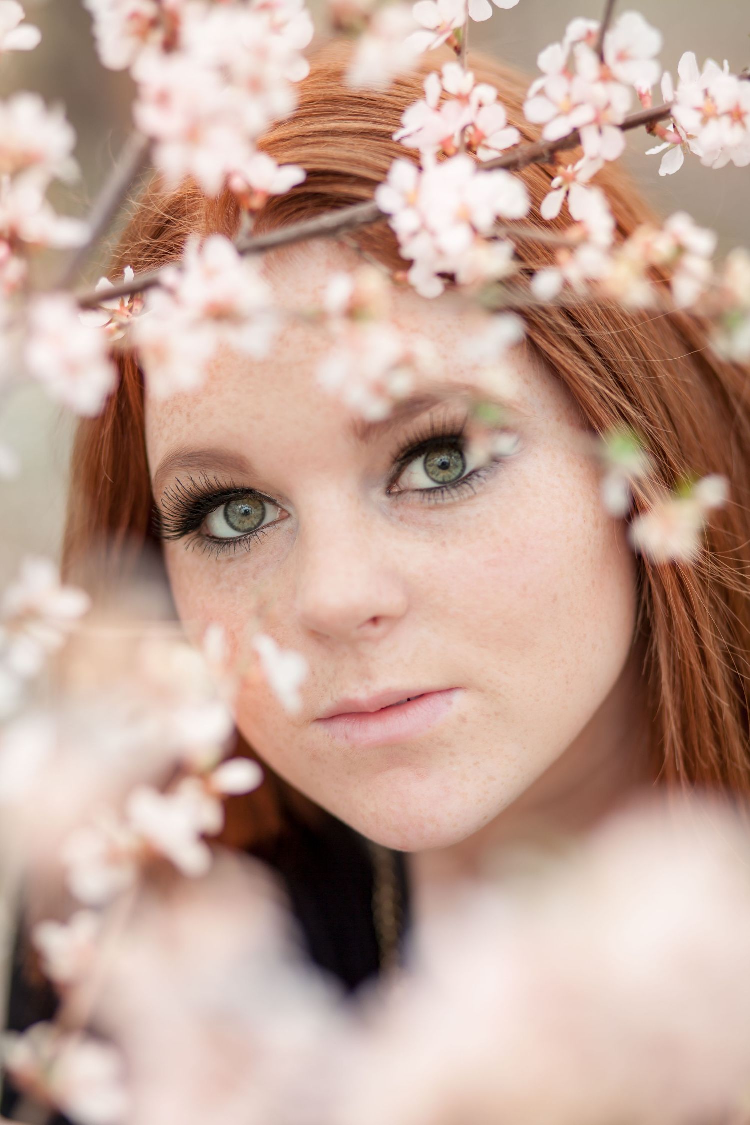Close-up portrait framed by delicate pink cherry blossoms.