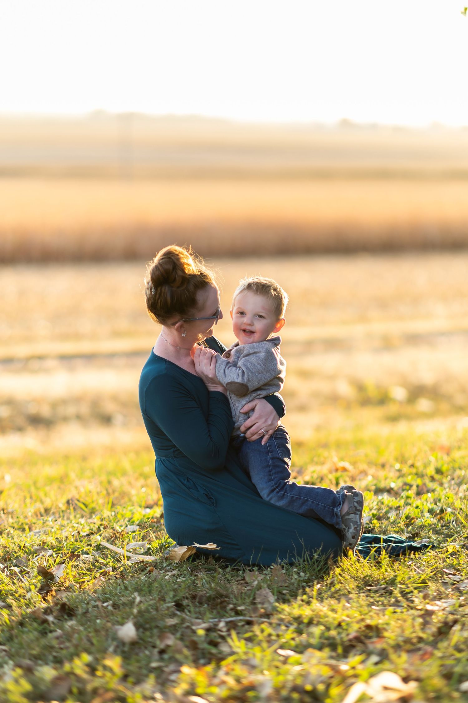 A person and baby share a tender moment in a golden field during sunset.