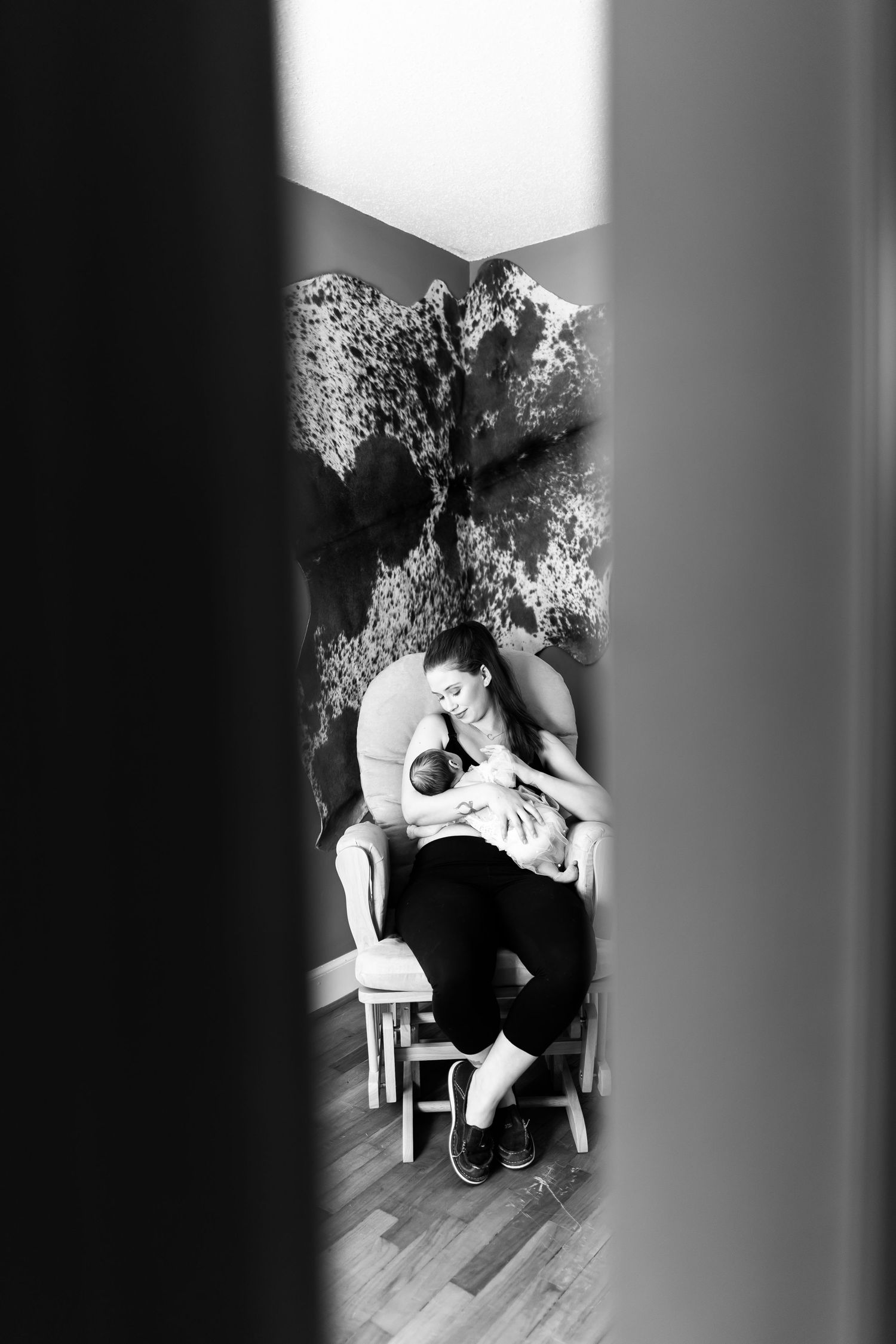 A black and white artistic portrait of a seated figure in a dramatic shadow and light composition.