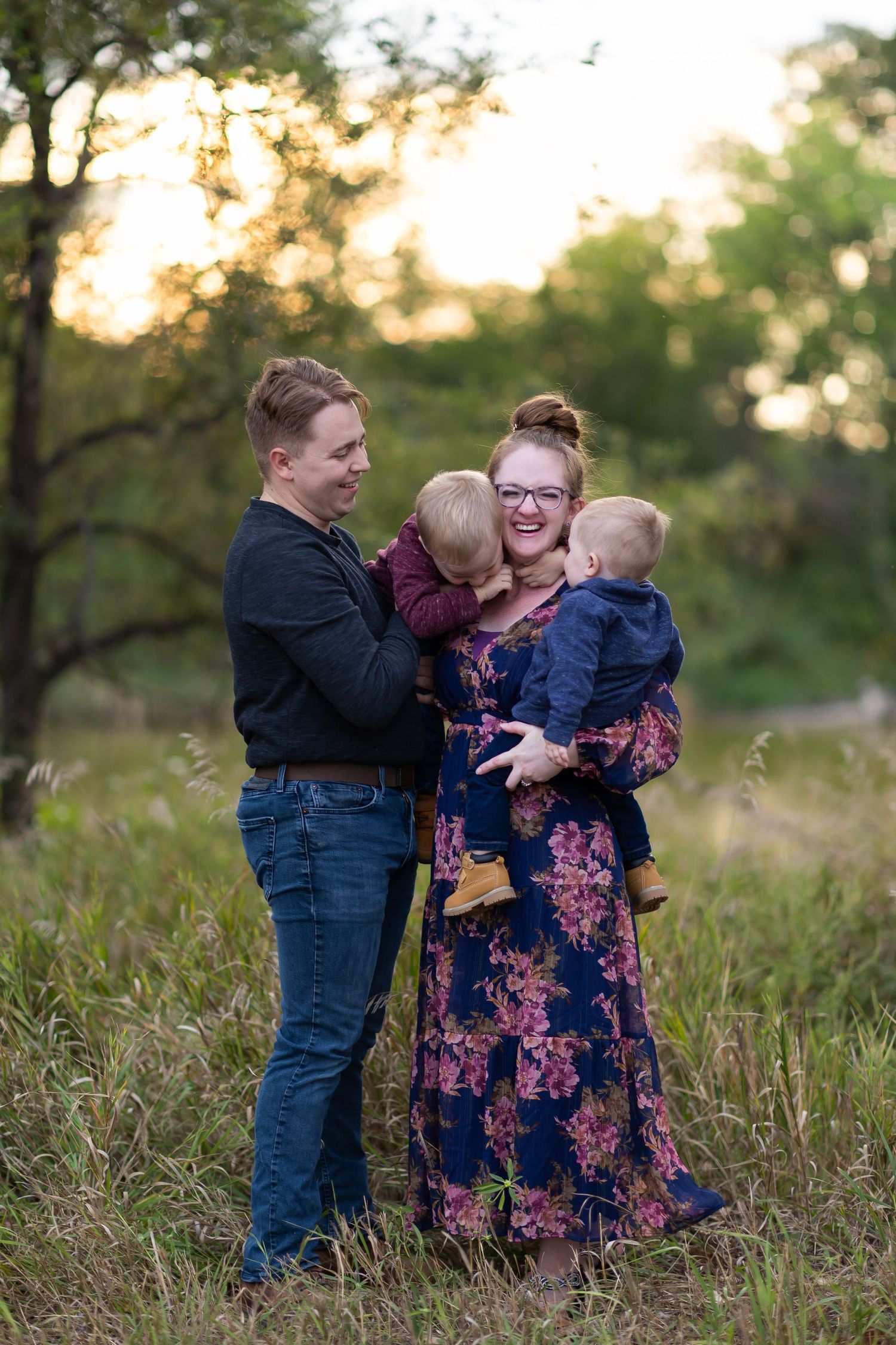 A family portrait in a field at sunset with two small children.