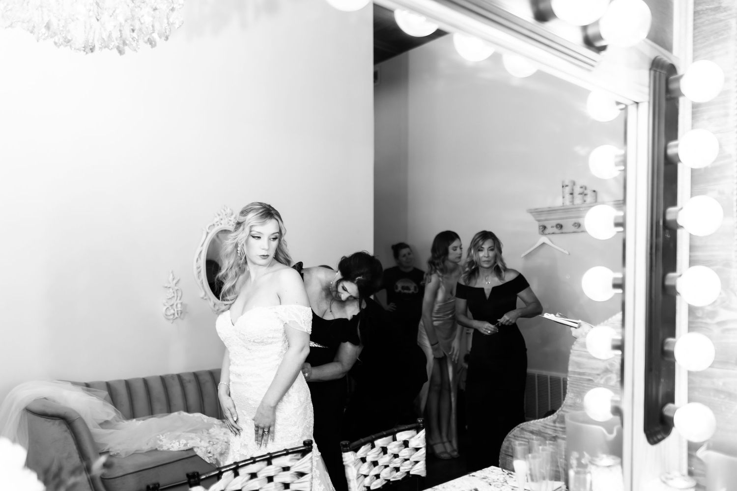 Black and white photo of wedding preparation scene in bridal suite with mirrors.