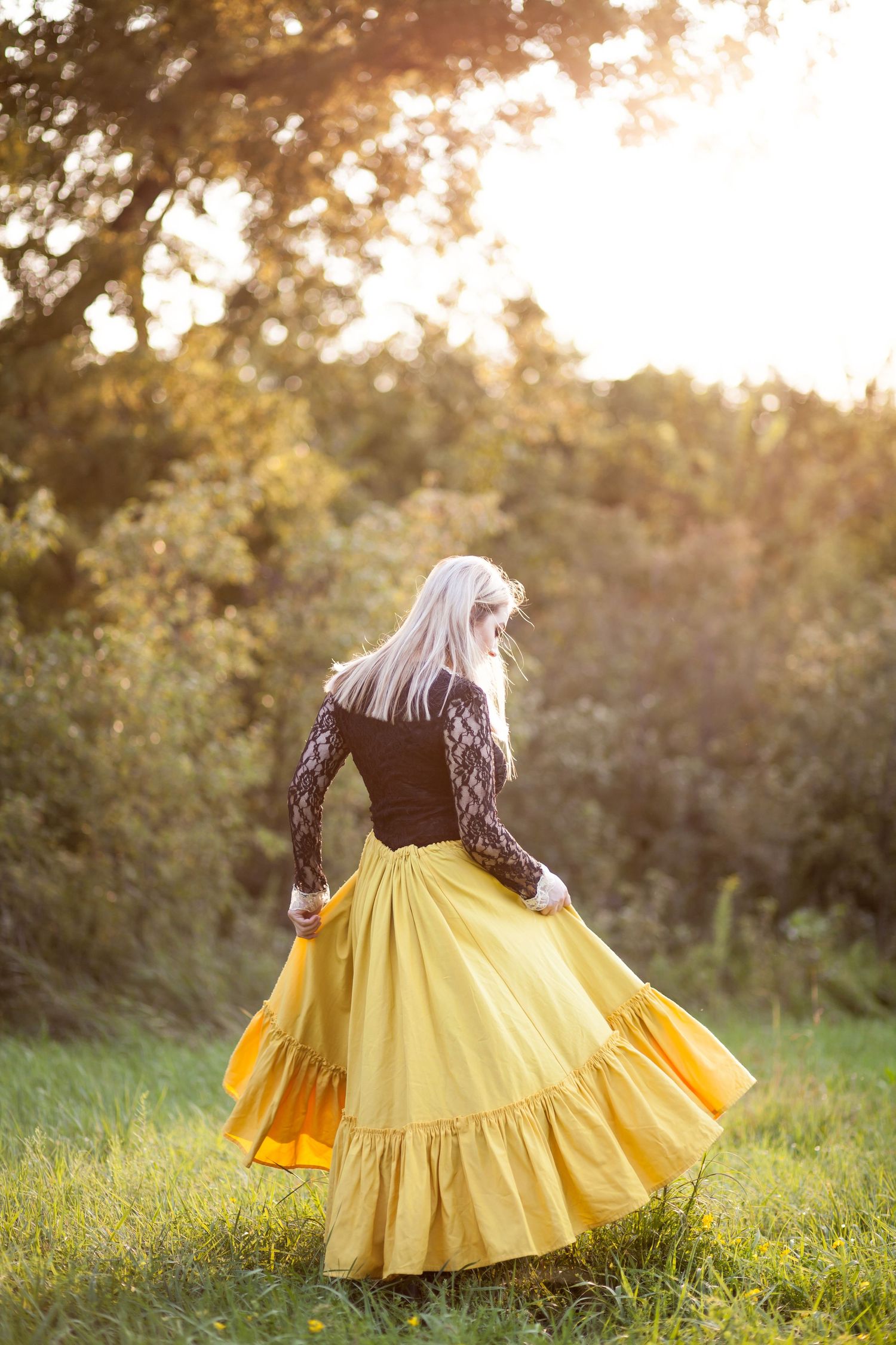 A flowing yellow skirt twirls against golden sunset light in a meadow.