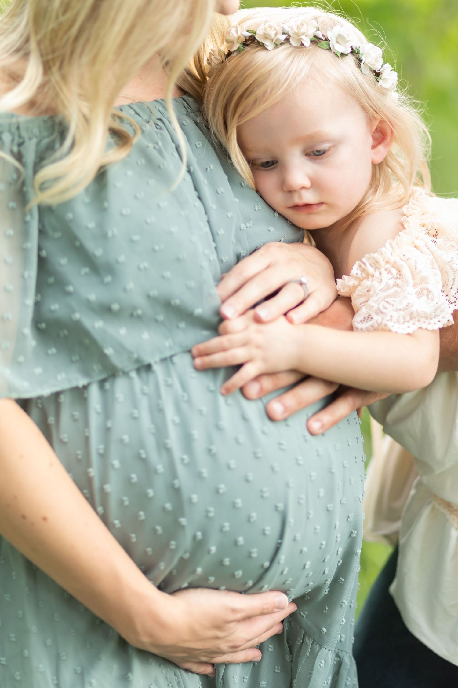 A tender maternity moment with flower crown between mother and child in soft lighting.