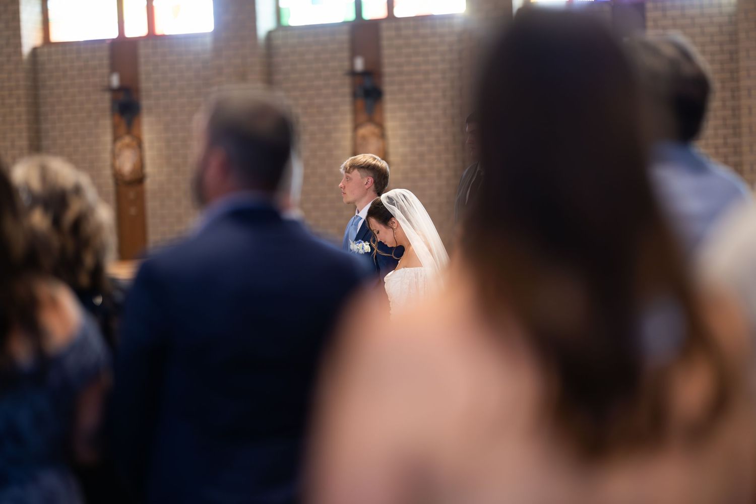 Bride and groom share first dance at church wedding ceremony with guests watching in background.