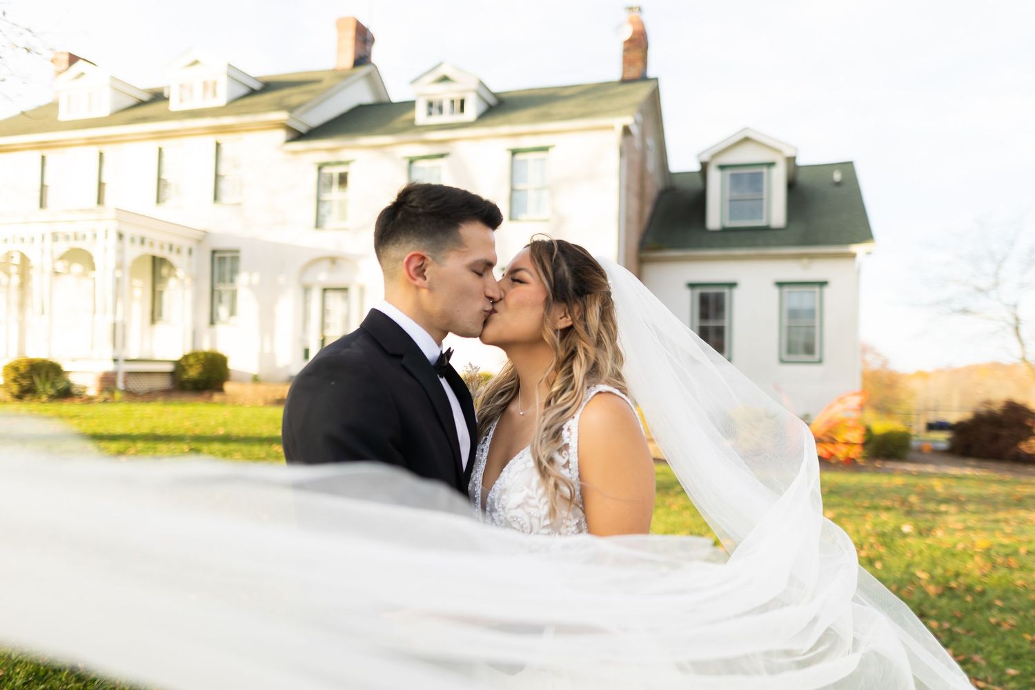 Wedding couple kissing with bride's veil dramatically flowing in the wind.