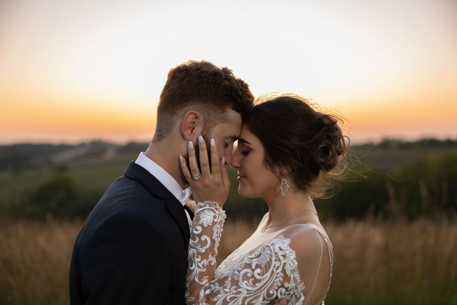 A couple shares an intimate moment at sunset in a golden field of tall grass.
