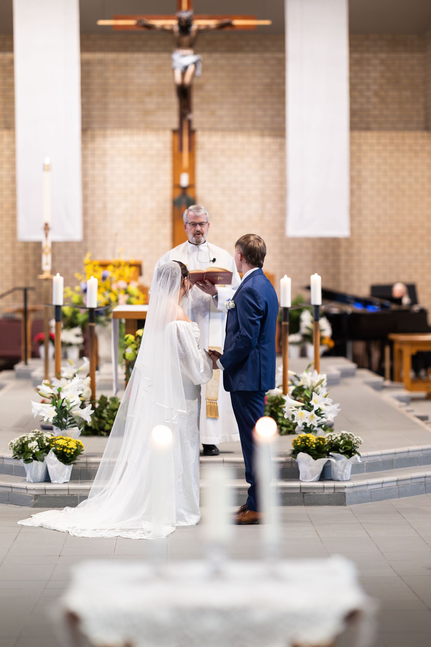 Bride and groom exchanging vows at a church altar with a priest officiating during a traditional wedding ceremony.