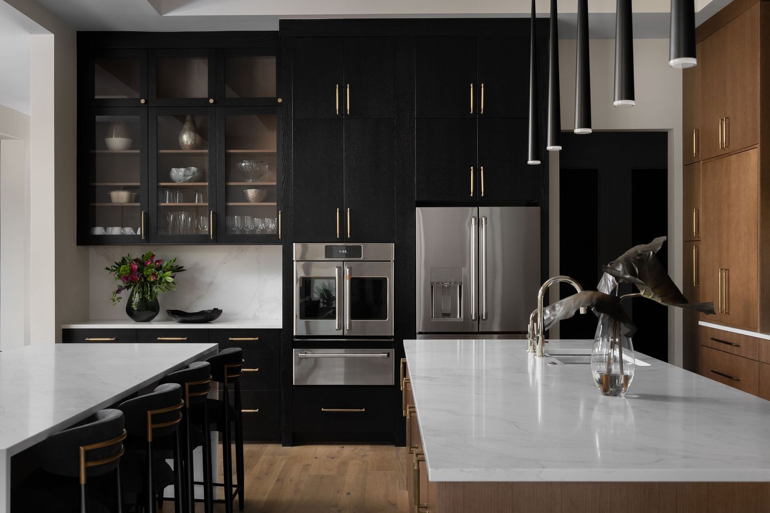 Modern kitchen with dark cabinetry, white countertops, and wood accents by Deanna Alban, Detroit interior designer.